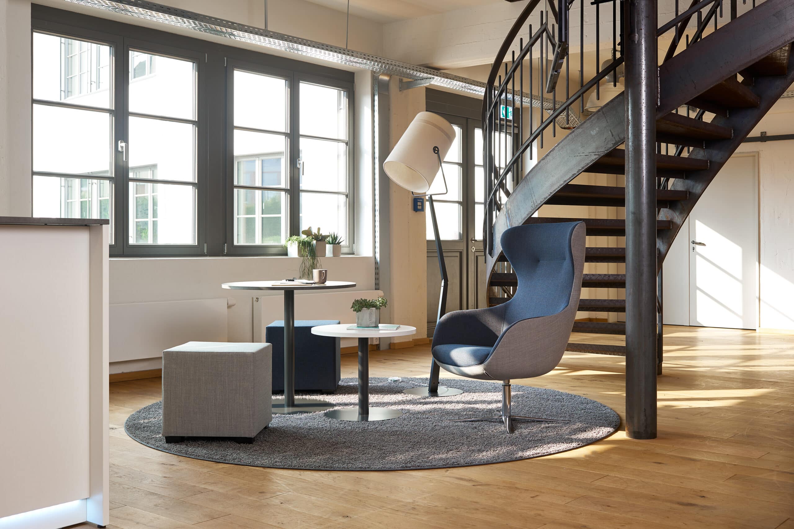Modernes Loft-Büro mit Wendeltreppe und gemütlicher Sitzecke.