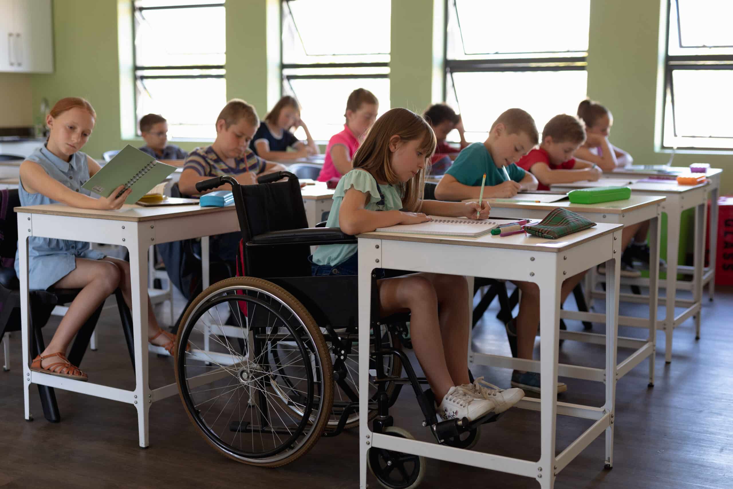 Kinder in Schulklasse beim Lernen mit Rollstuhl