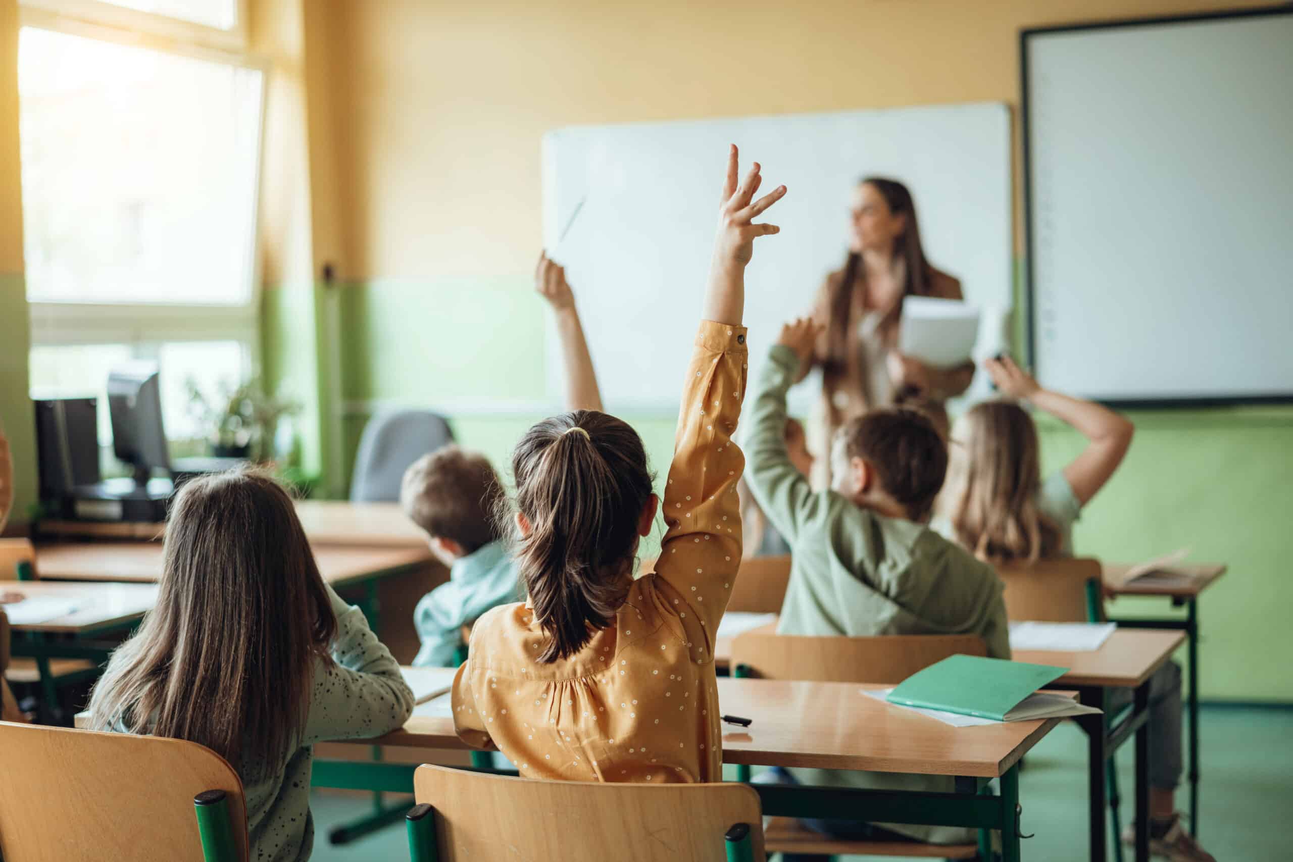 Kinder im Klassenzimmer mit erhobenen Händen