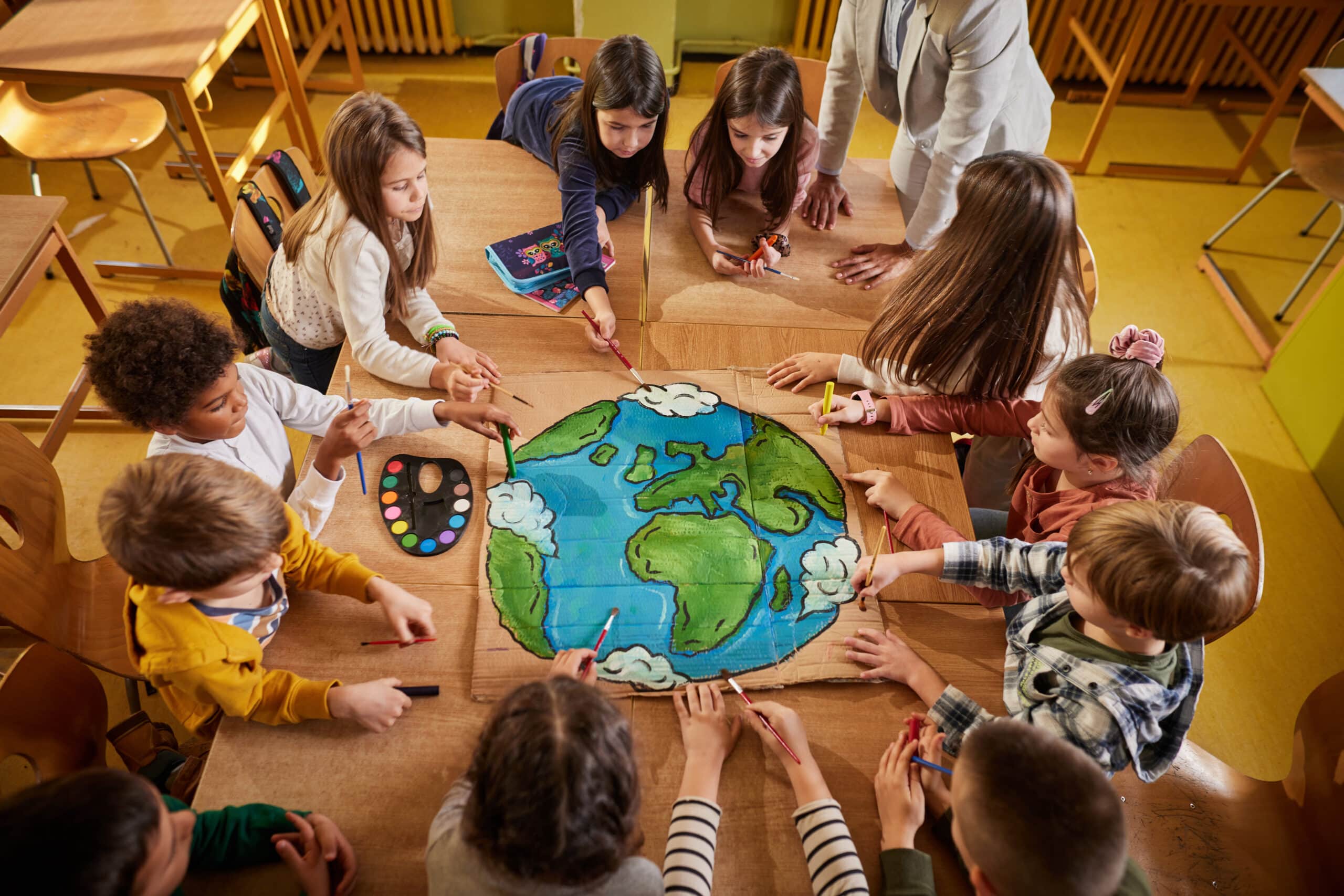 High angle view of elementary students painting a planet during an art class in the classroom.
