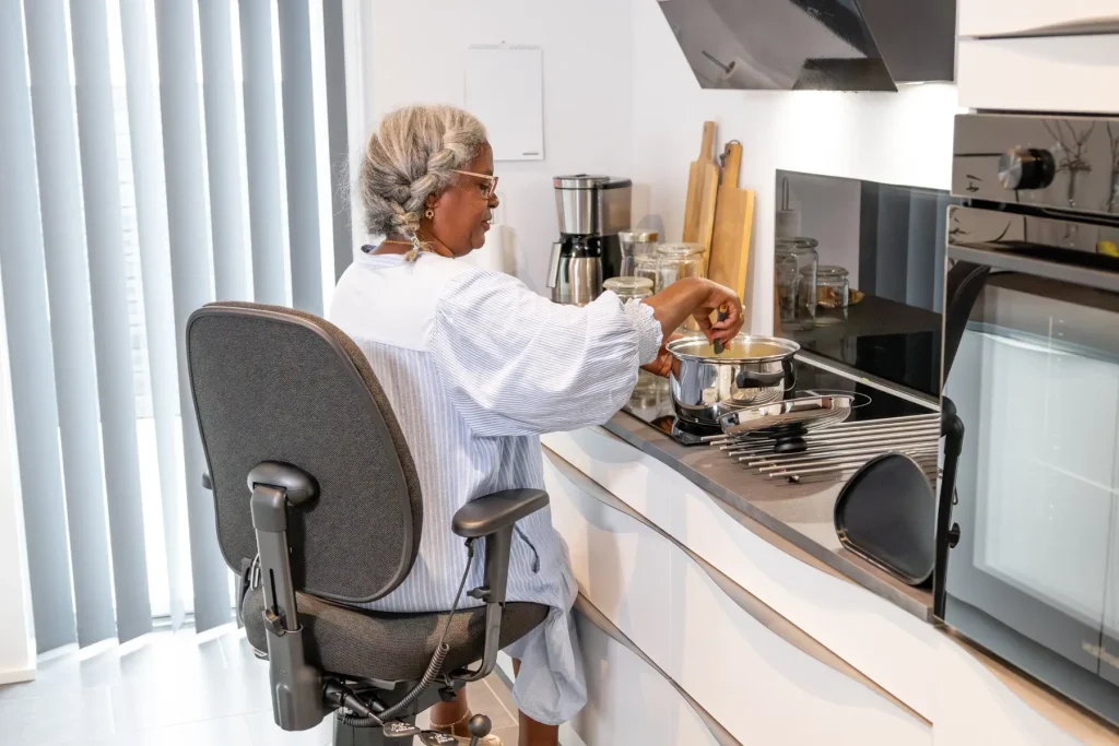 Frau bereitet im Sitzen auf einem VELA Trippelstuhl eine Mahlzeit zu
