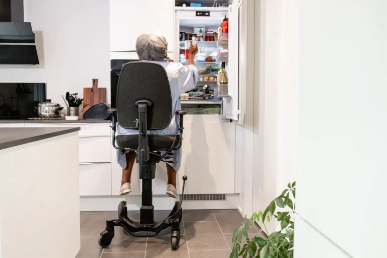 Person erreicht im Sitzen den Kühlschrank